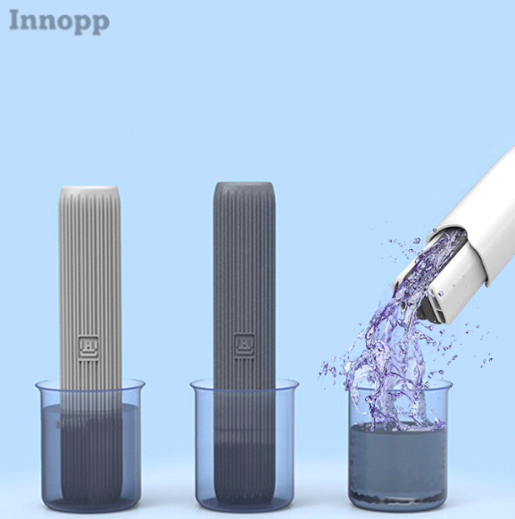 Drie mini-dweilen, waarvan twee in heldere bakken met water staan en de derde bak opgevuld wordt met violet water uit een aanvoerbuis.